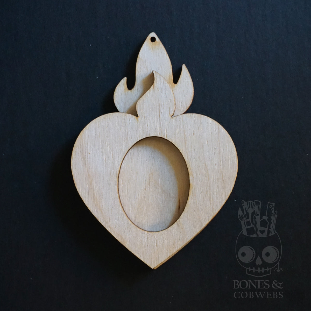 Wooden heart-shaped pendant with flame design on a black background